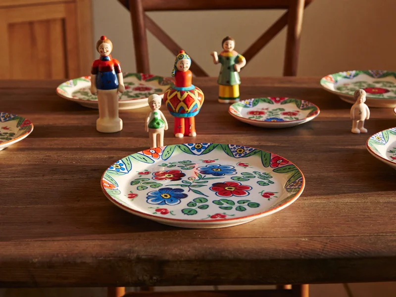 Farfurii decorative pictate manual și figurine mici pe o masă rustică din stejar