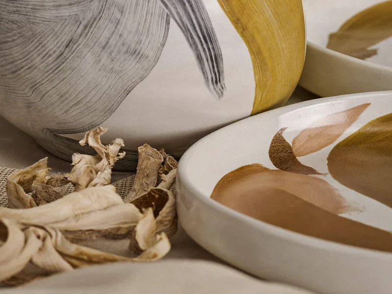 Detaliu de glazură ceramică și tușe de pensulă lângă așchii de lemn și in